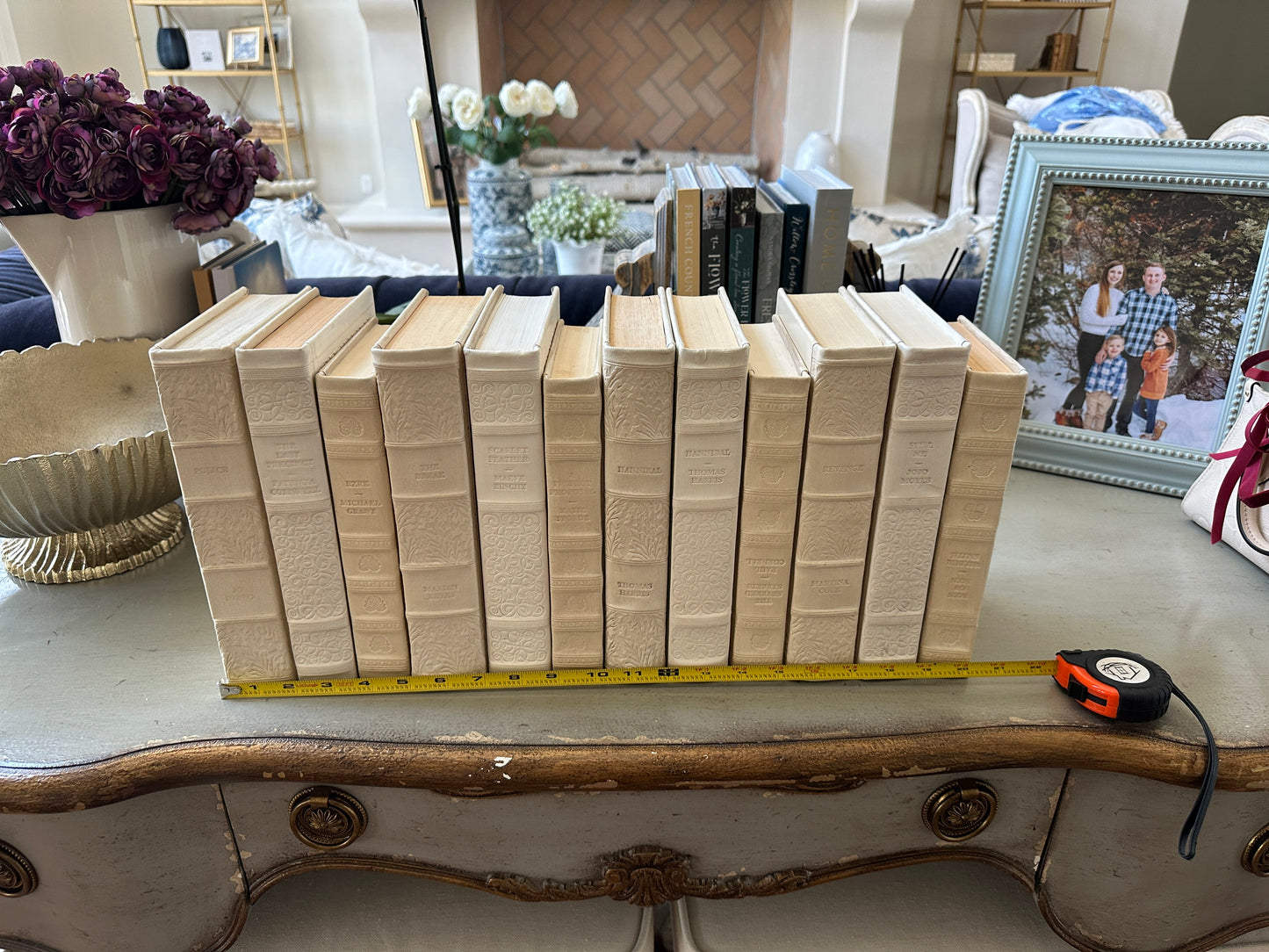 Row of books on a table with a measuring tape in a home setting
