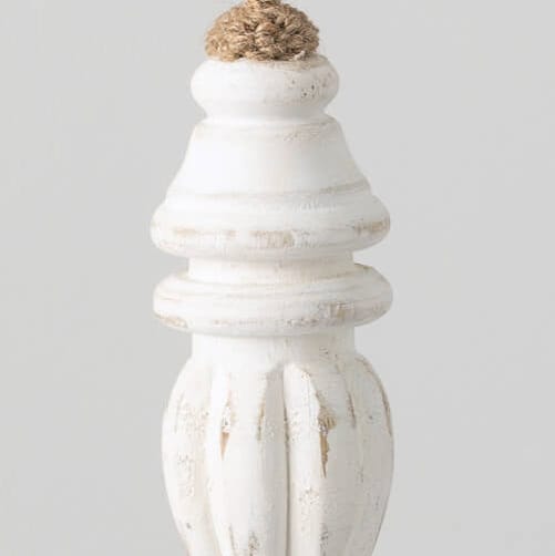 A white washed wood finial ornament hanging from twine against a light background.