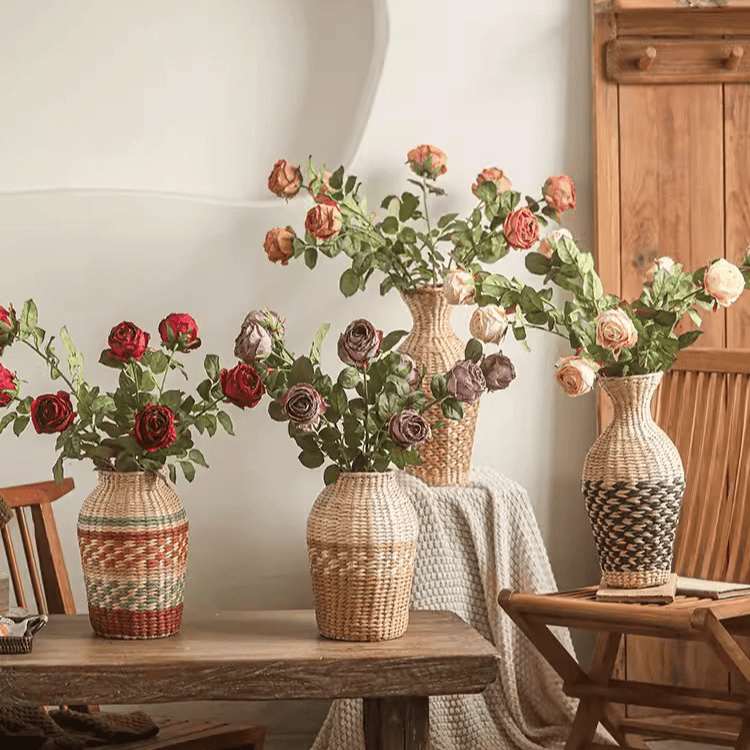 Decorative wicker vases with floral arrangements on a wooden table.