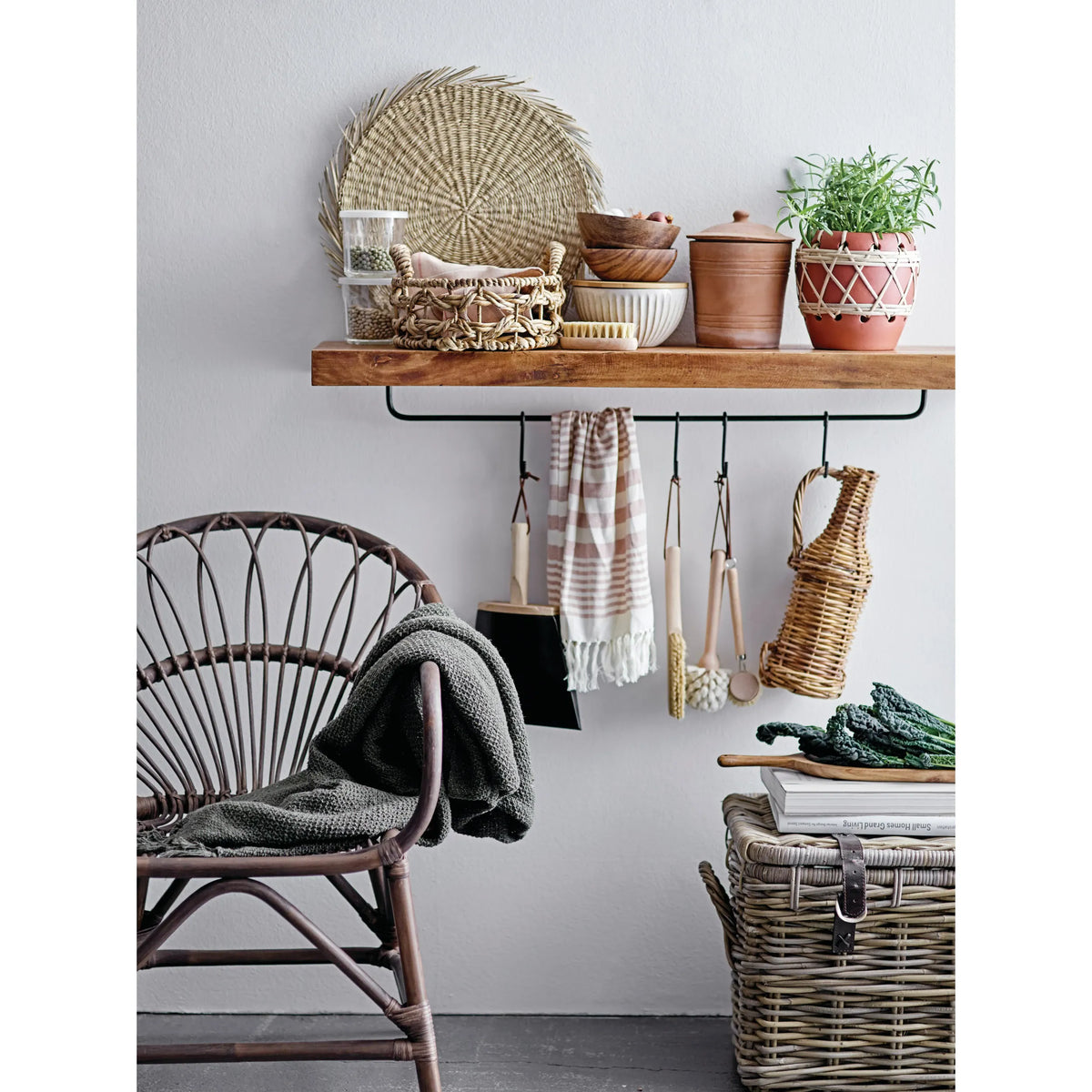 Set of cleaning tools including brushes and a dustpan on a wooden shelf against a white wall.