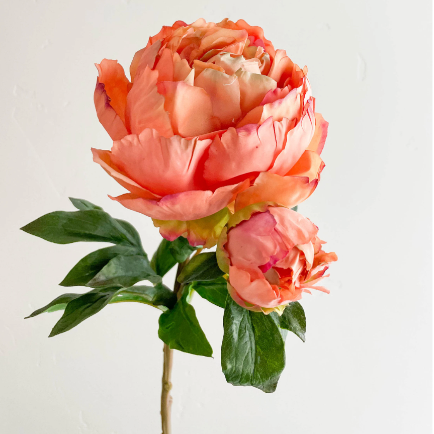 Artificial peach-colored peony flower arrangement on a white background
