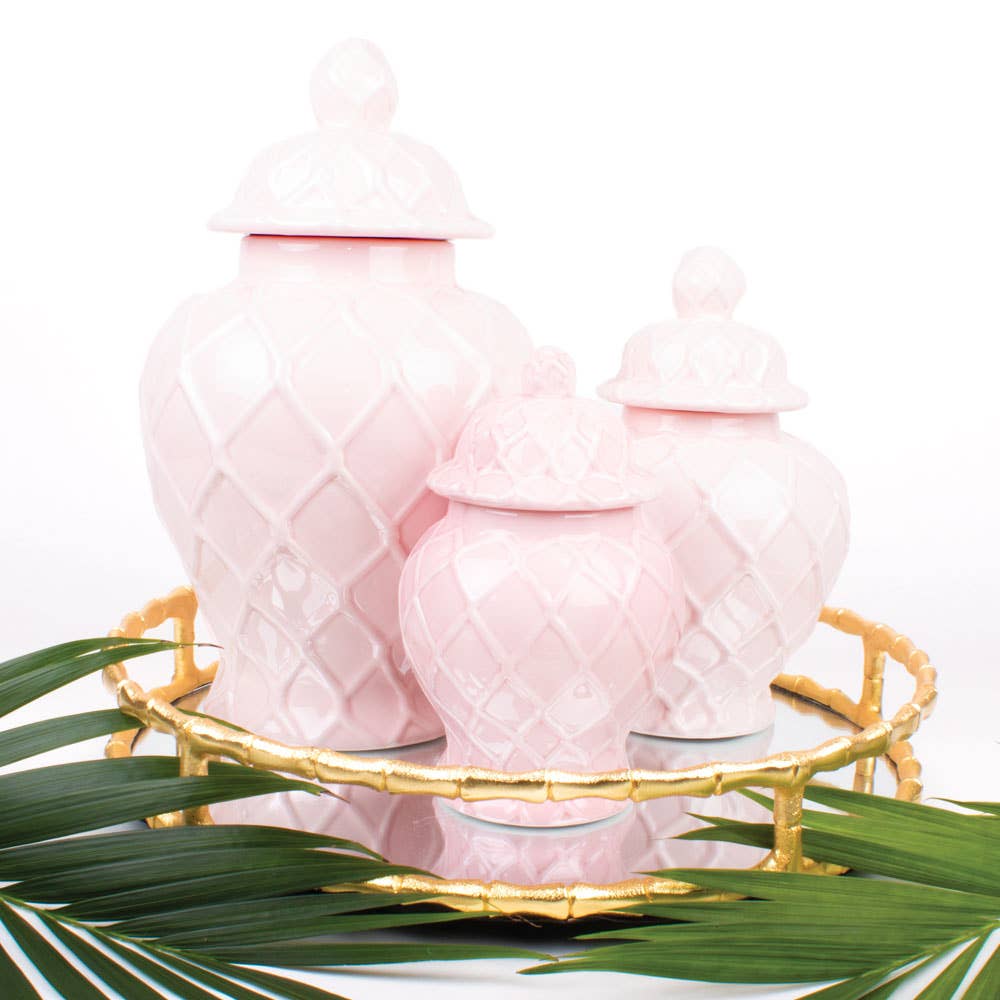 Pink textured vases on a gold tray with green leaves on a white background