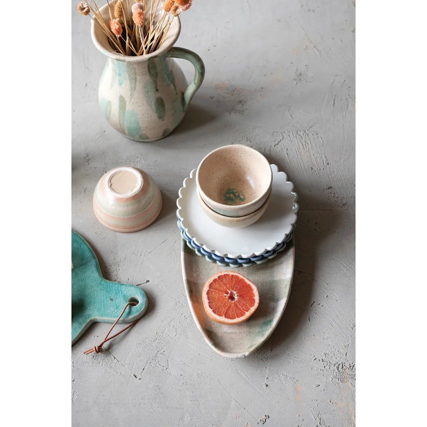 A set of three stoneware plates with scalloped edges, in blue, cream, and green colors.