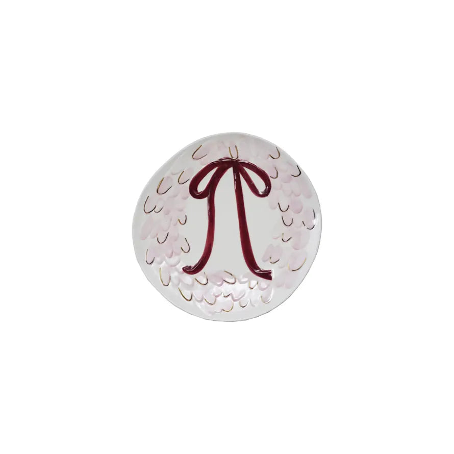 White and pink plate with a red bow design on a white background.