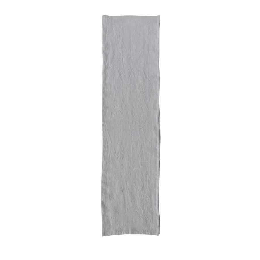 A beige linen table runner with a stonewashed texture visible.