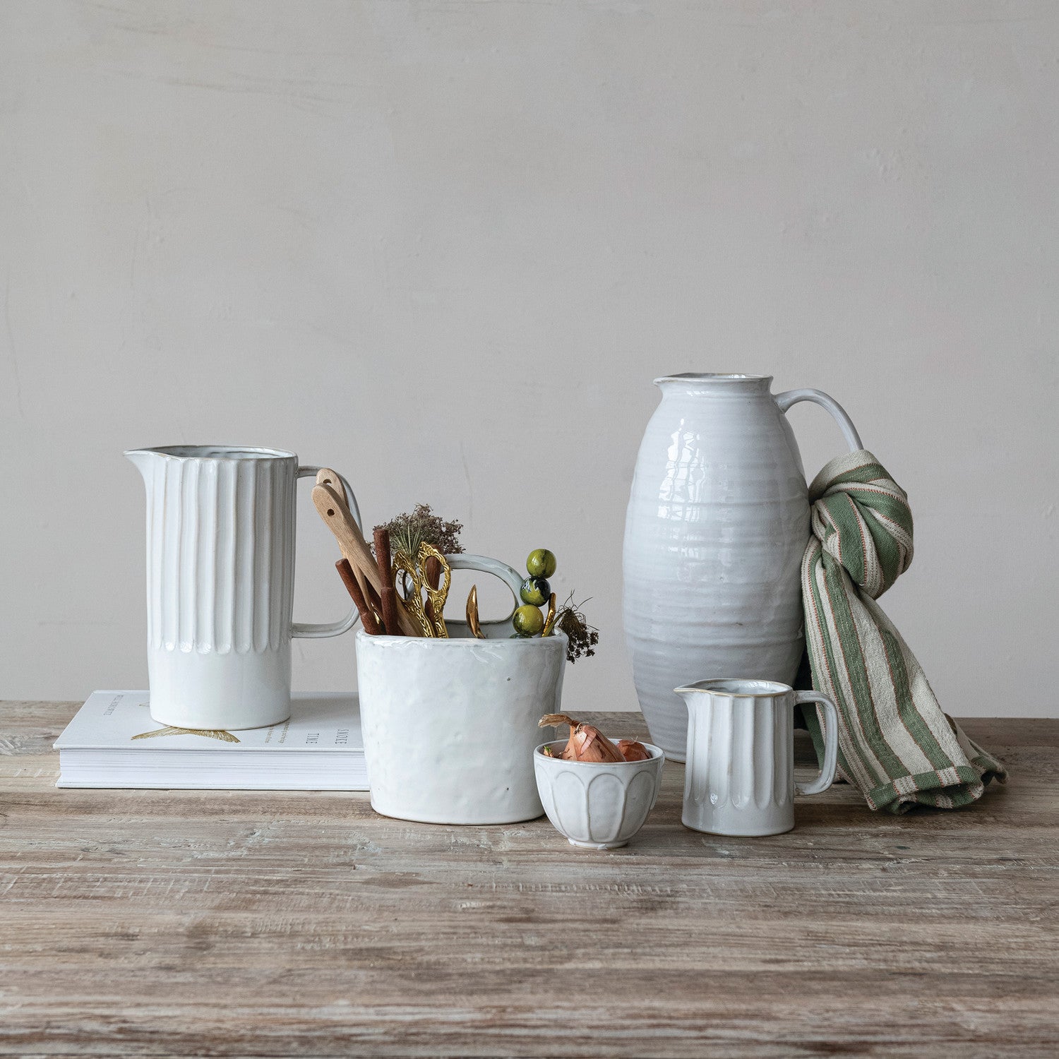 Set of ceramic pots and vases on a wooden surface with a neutral background