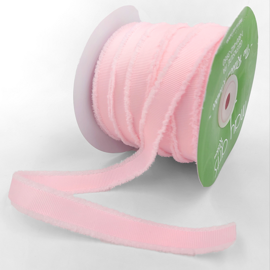 Pink ribbon on a spool with a green label on a light gray background