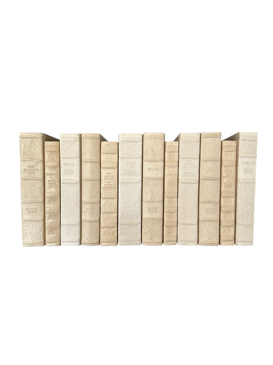 A set of English fine leatherbound books in shades of antique white, arranged in a row.