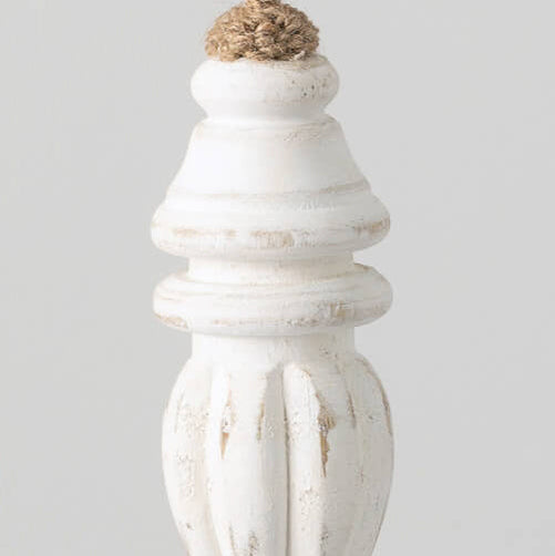 A white washed wood finial ornament hanging from twine against a light background.