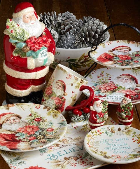 Decorative Christmas table setting with Santa Claus figurines, plates, and a teapot.
