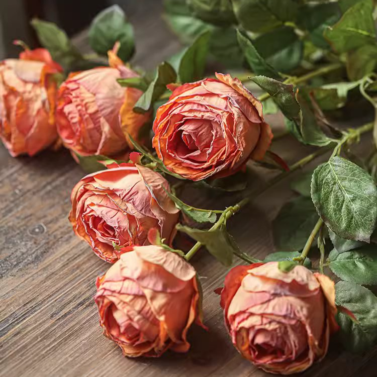 Dried roses with green leaves on a wooden surface
