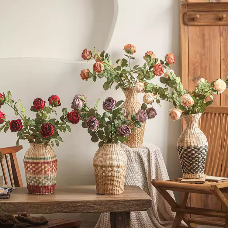 Decorative wicker vases with floral arrangements on a wooden table.