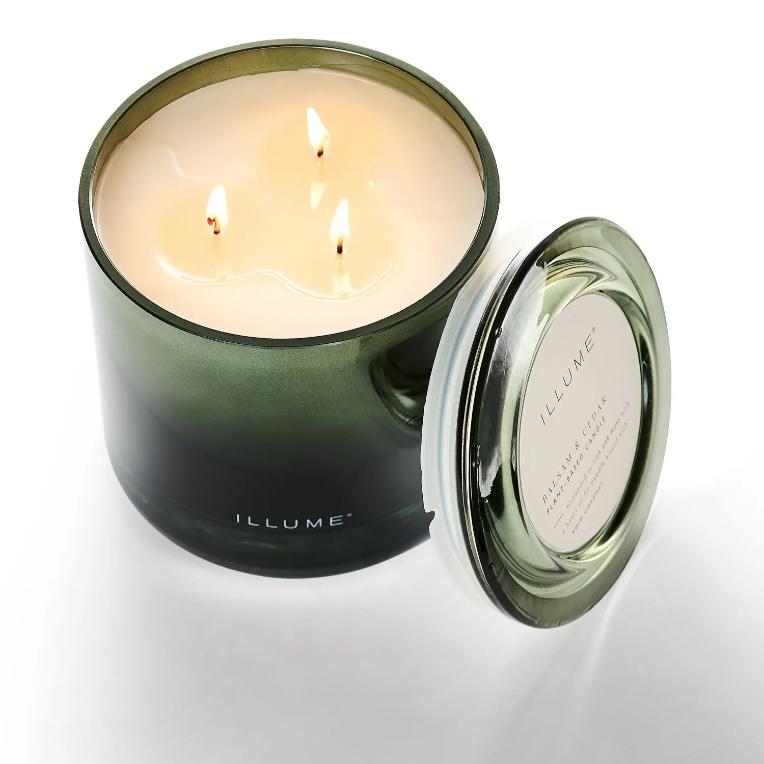 Green glass candle with a lit wick