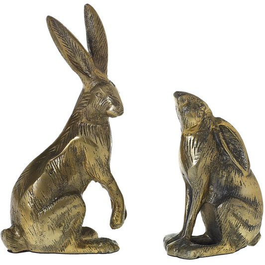 Two bronze candlestick holders in the shape of rabbits, one facing forward and one facing to the side.