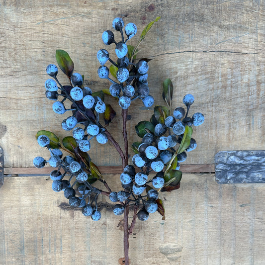 Artificial blue berry branch on a wooden surface