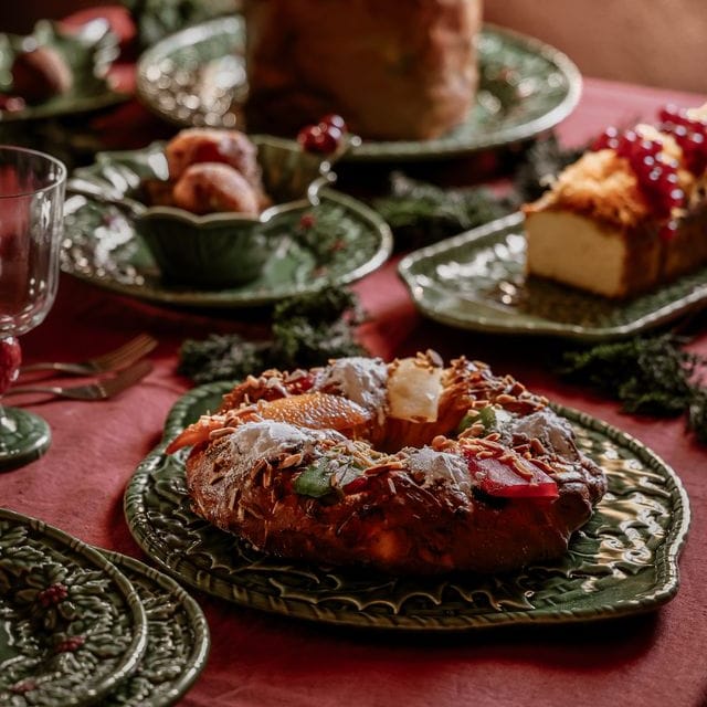 Decorative table setting with festive bread and pastries on a red tablecloth.