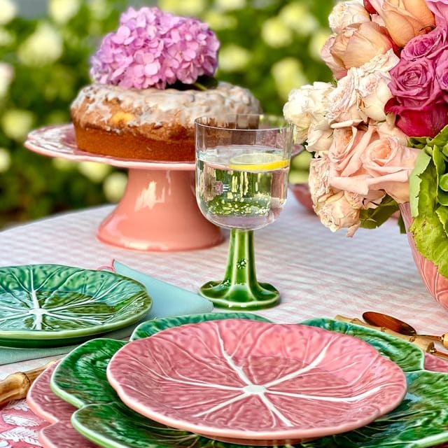 Outdoor table setting with decorative plates, cake, and flowers.