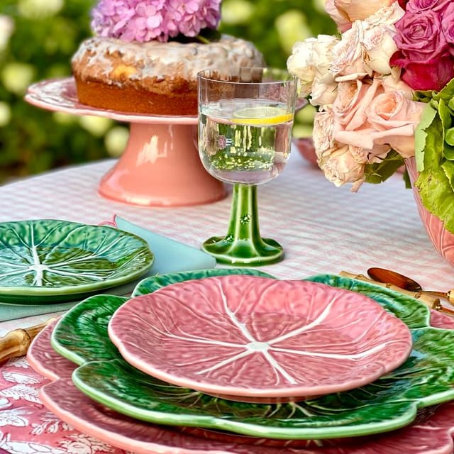 Outdoor table setting with decorative plates, cake, and flowers.