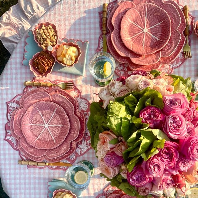 Decorative table setting with pink cabbage plates, flowers, and a checkered tablecloth.