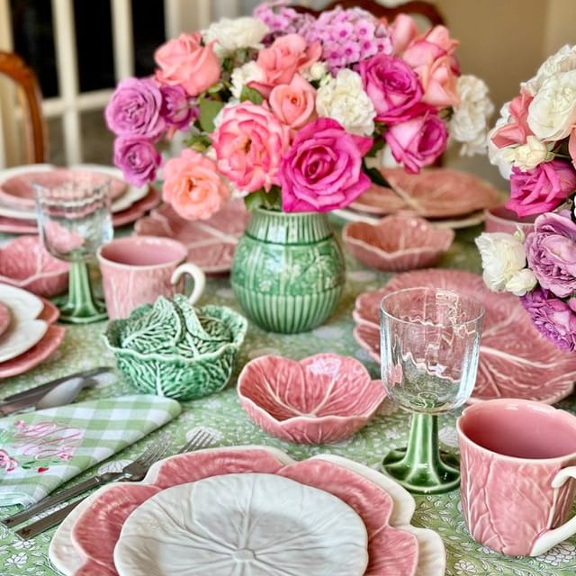 Decorative table setting with pink and green floral arrangements and ceramic plates.