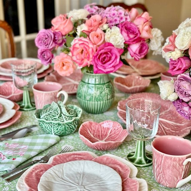Decorative table setting with pink and green floral arrangements and ceramic plates.