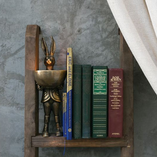 A brass-gold finished metal stand in the shape of a rabbit holding a bowl.