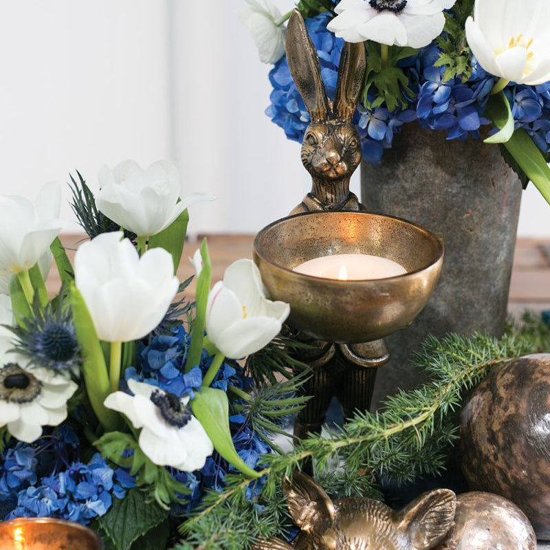 A brass-gold finished metal stand in the shape of a rabbit holding a bowl.
