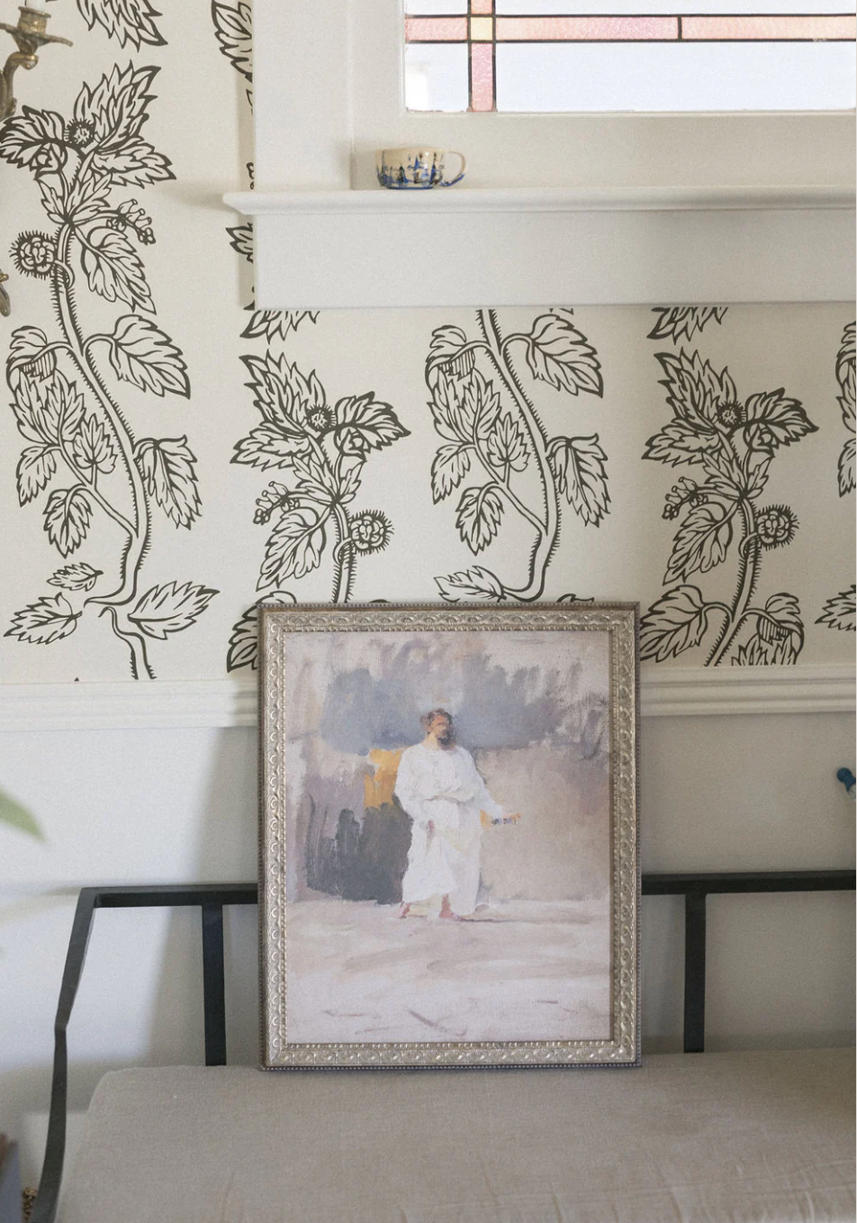 Framed Christ artwork on a wall with decorative floral wallpaper