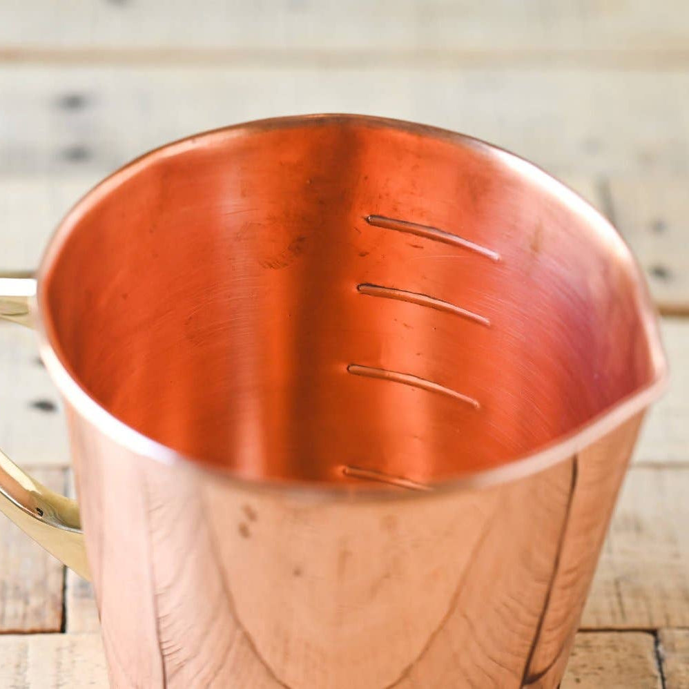 Copper measuring cup on a wooden surface