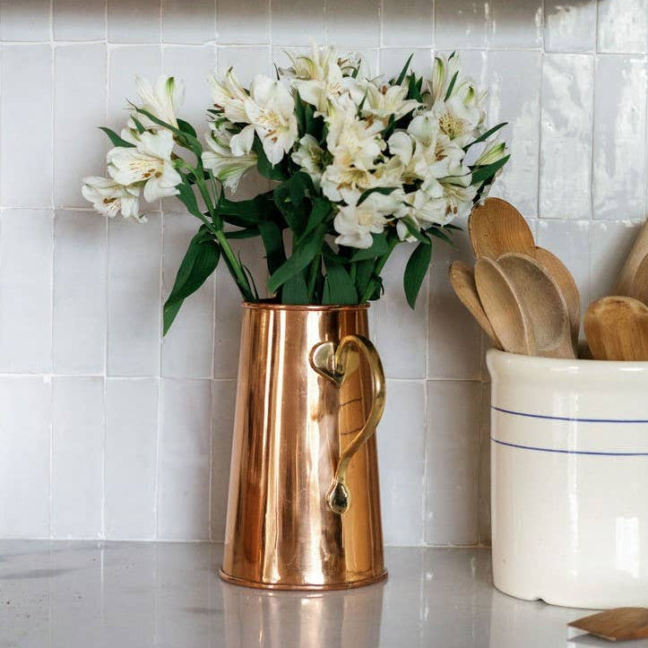 Copper pitcher with white flowers on a kitchen counter