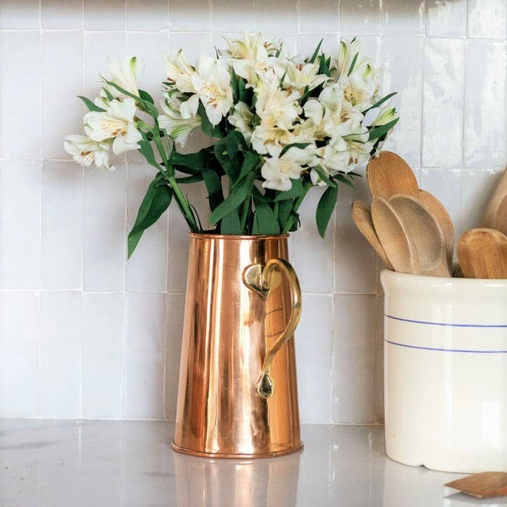 Copper pitcher with white flowers on a kitchen counter