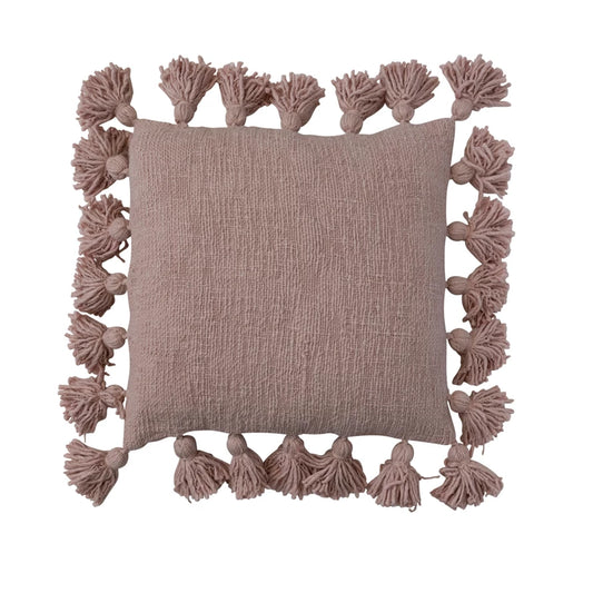 A square-shaped dusty pink cotton slub pillow with tassels on the edges.