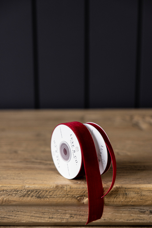 Spool of red ribbon on a wooden surface with a dark background