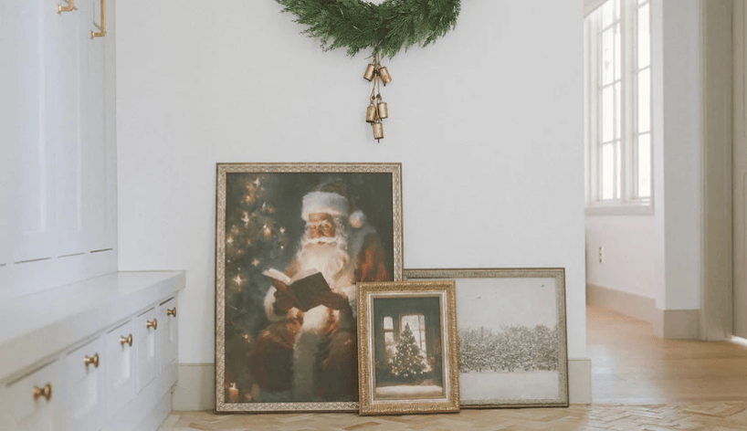 Decorative Christmas scene with Santa Claus artwork and wreath on a white wall.