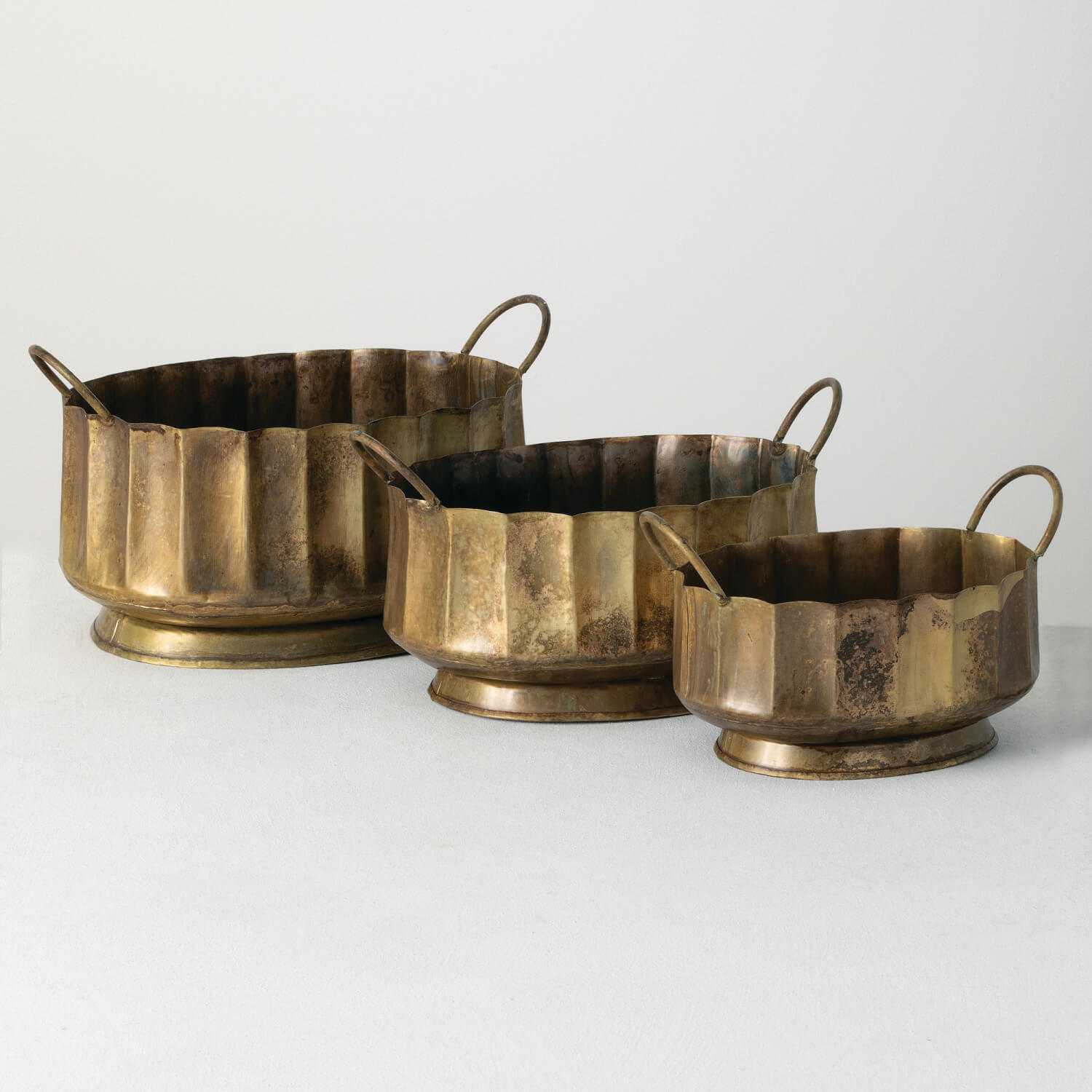 A set of three gold handled bowls in varying sizes, with a bronze-colored finish.