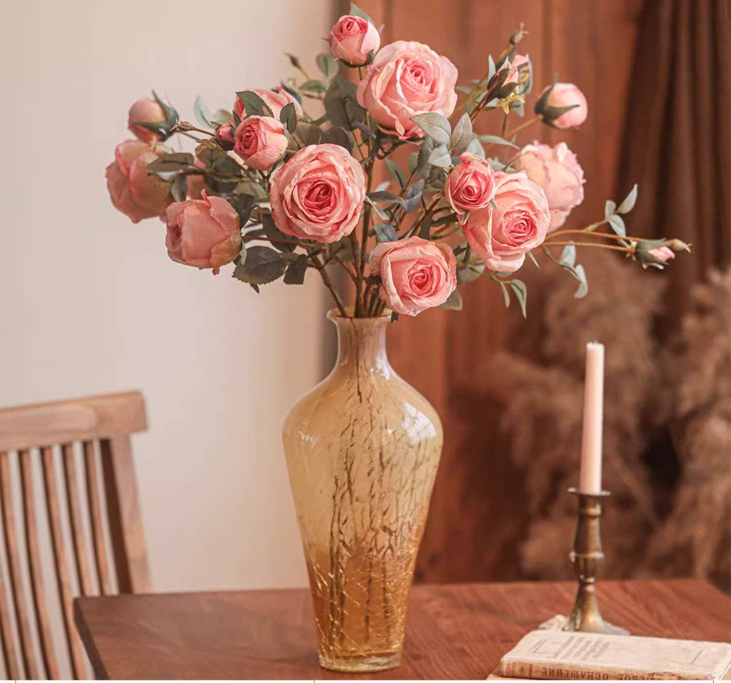 Vase with pink roses on a wooden table in a softly blurred room setting