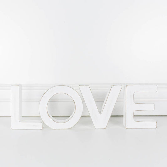 A white wooden cutout letter 'L' with the word 'LOVE' made out of cutout letters, standing upright against a white background.