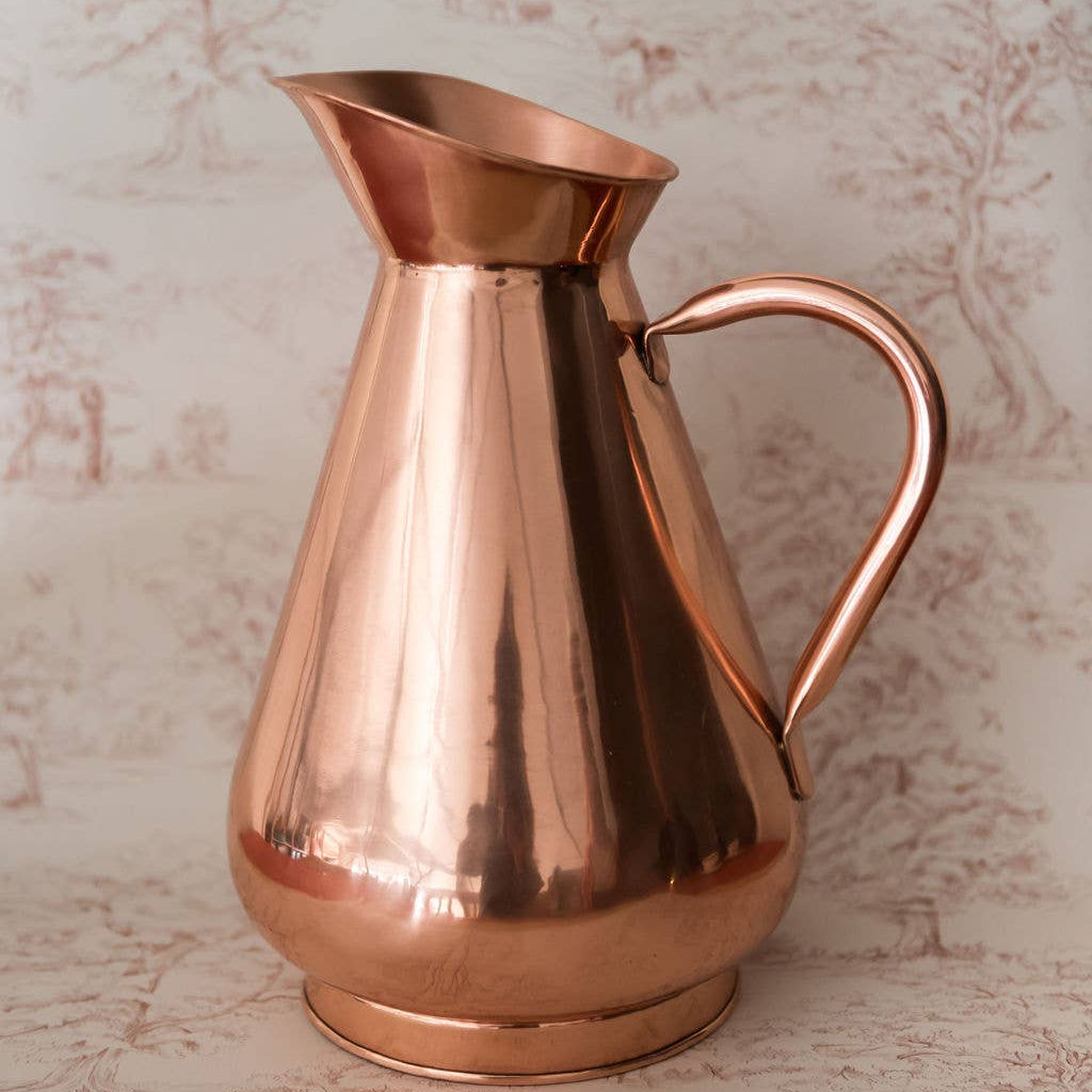 Copper pitcher on a textured beige background