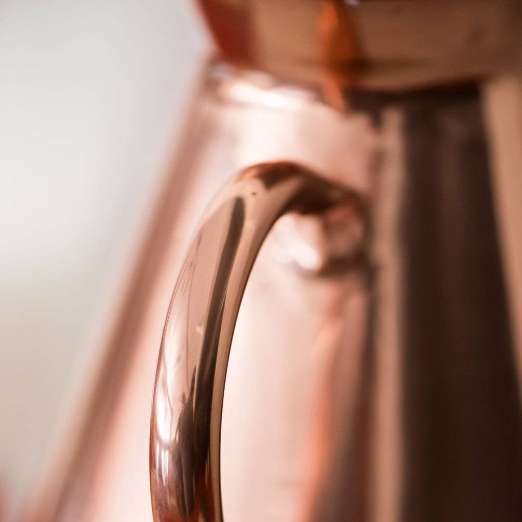 Close-up of a copper pitcher with a blurred background