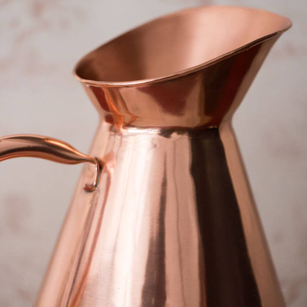Copper pitcher on a neutral background