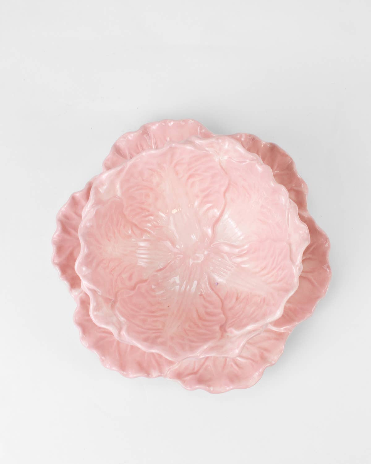 Pink ceramic cabbage bowl and plate plate with scalloped edge on a light gray background
