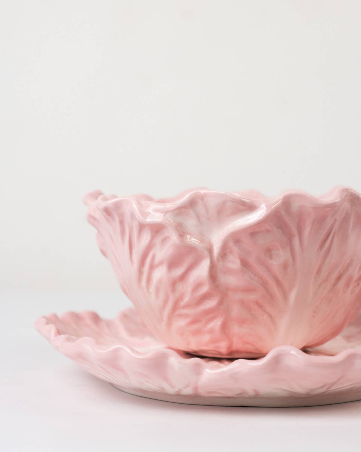 Pink ceramic cabbage leaf bowl with textured surface on a light gray background