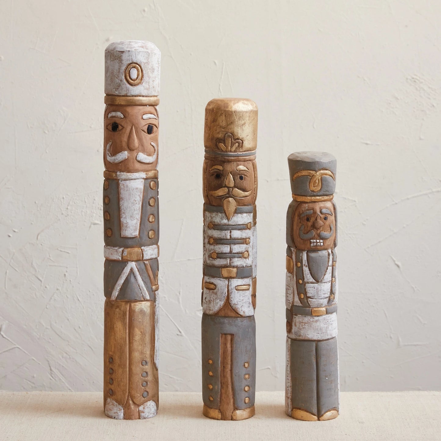 A set of three hand-carved mango wood nutcracker statues in varying sizes, featuring a multicolor design with white, gold, and gray tones.