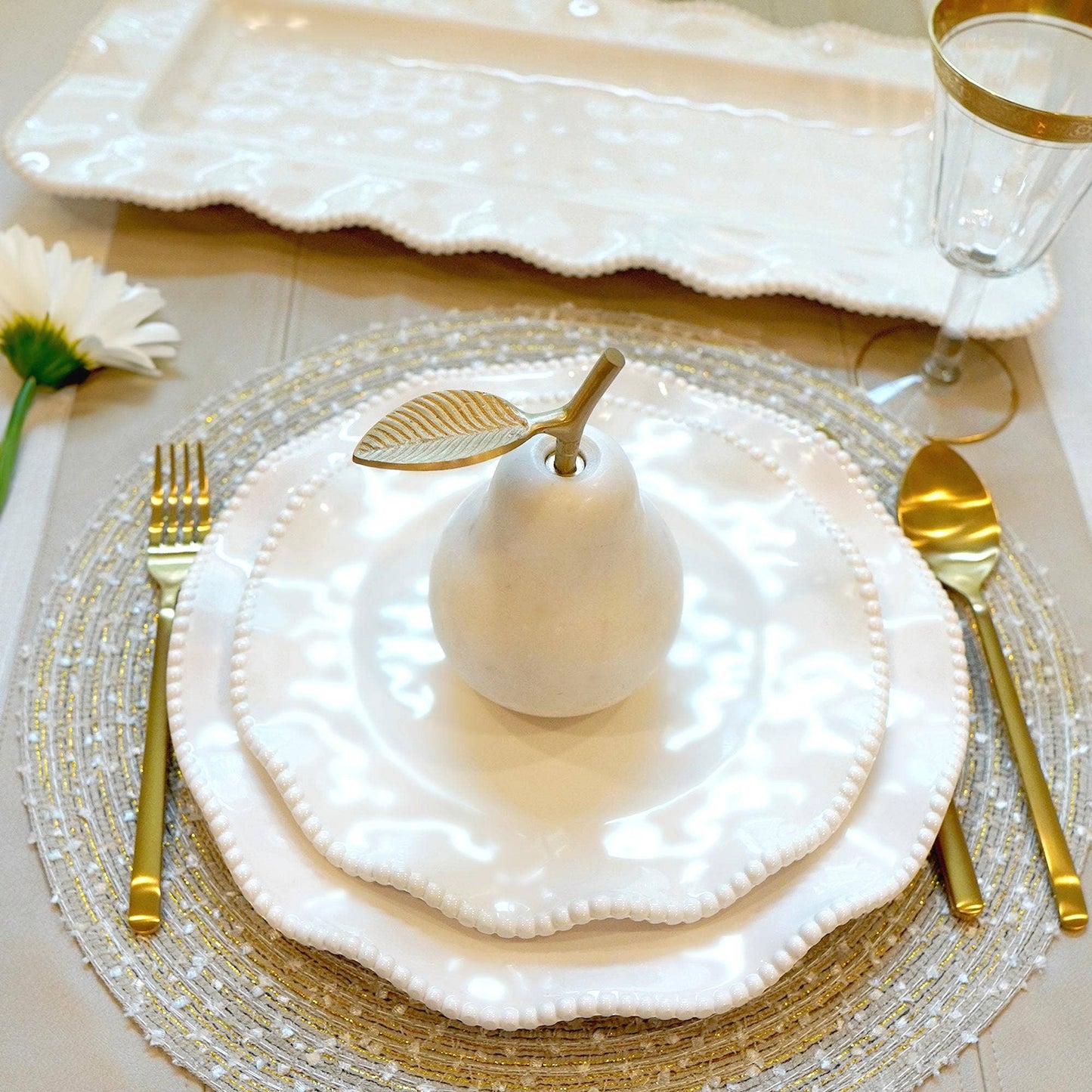 Elegant table setting with white melamine plates, gold cutlery, and decorative elements on a beige surface.