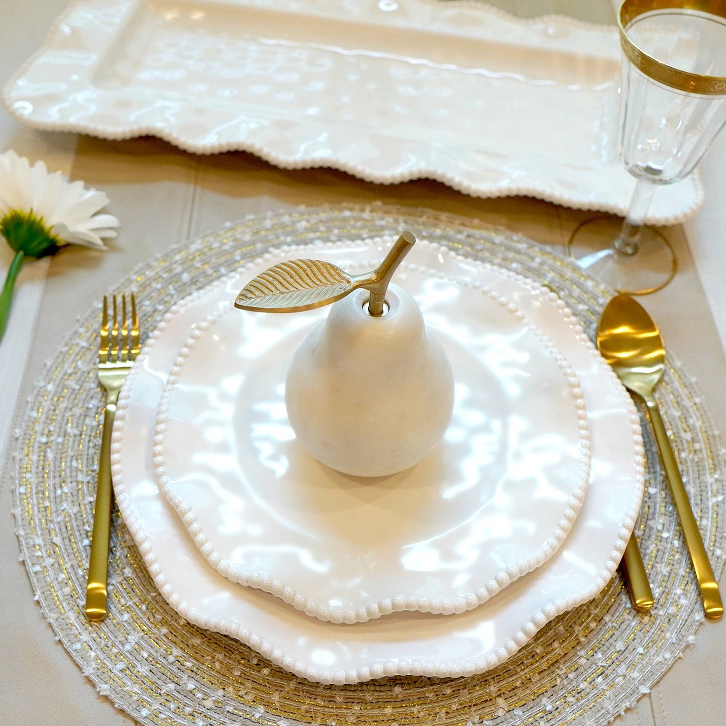 Elegant table setting with white plates, gold cutlery, and decorative elements.