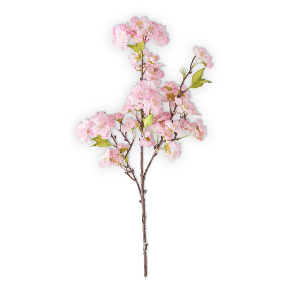 A artificial cherry blossom spray with pink flowers and green leaves on a brown branch, isolated on a white background.