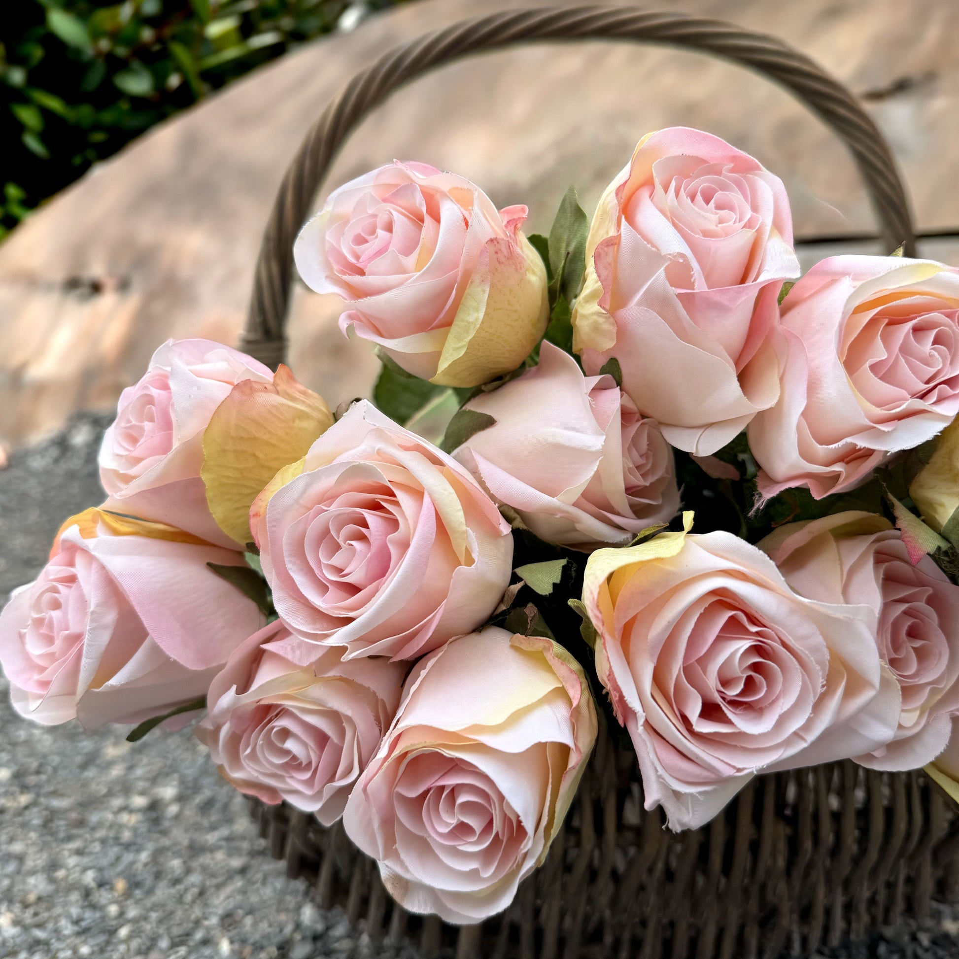 Basket of pink roses on a stone surface