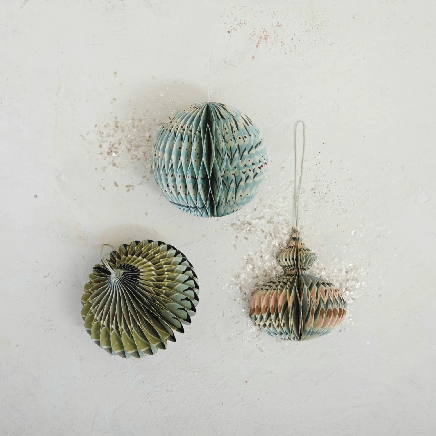 Three round paper folding honeycomb ornaments with multicolor patterns, laid out on a flat surface.