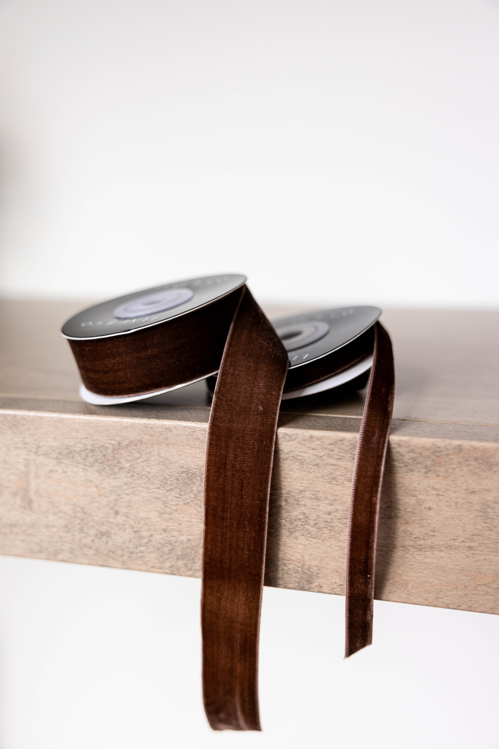 Brown ribbon spool on a wooden surface with a white background