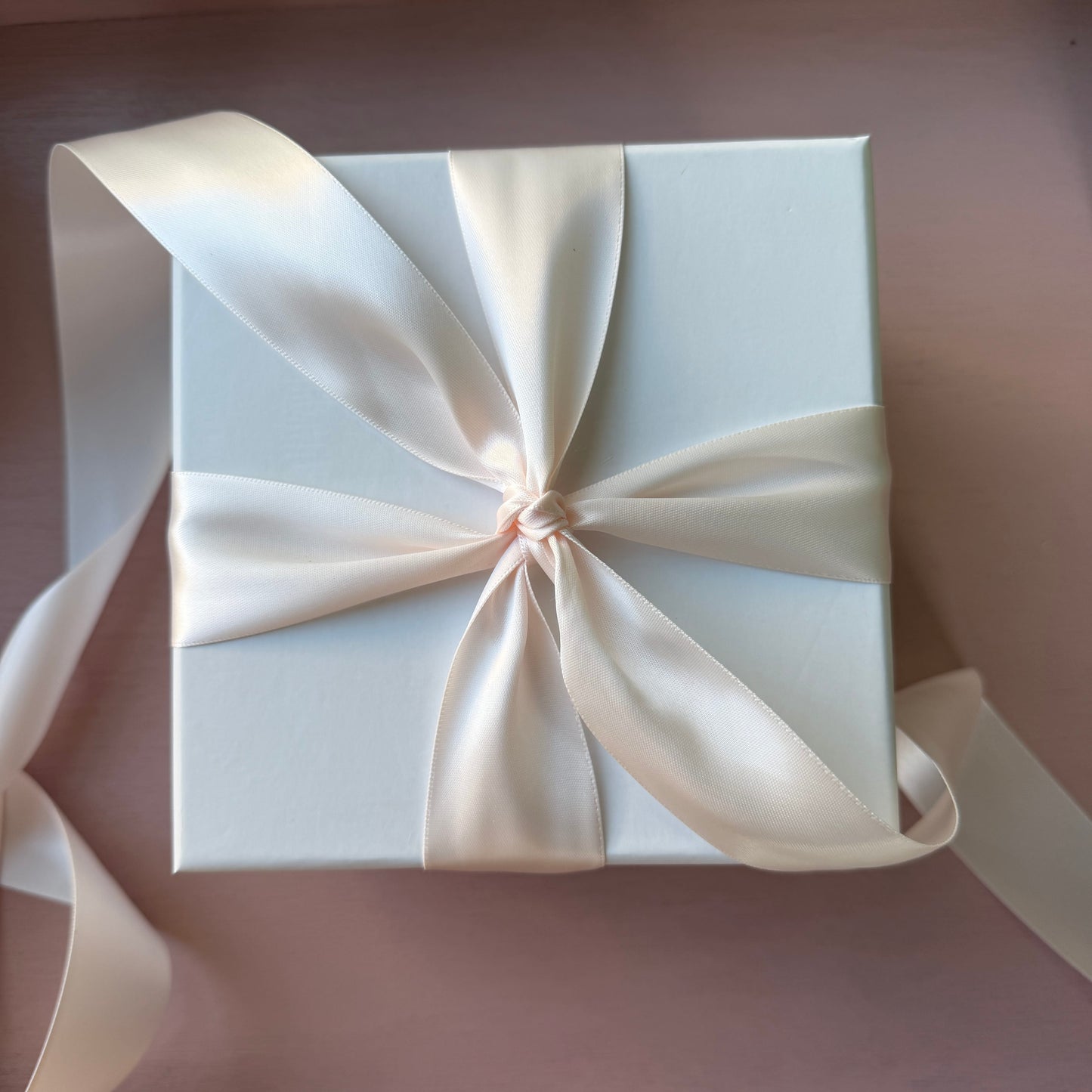 White gift box with a large bow on a matching background